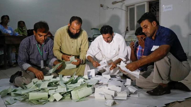 Election officials count votes after polling stations closed during the general election in Karachi